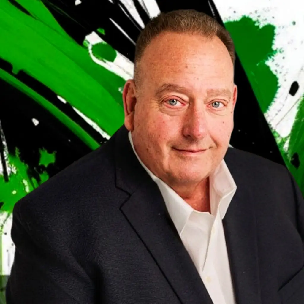 Portrait of a middle-aged man in a dark suit and white shirt, smiling, with a green and black abstract background.