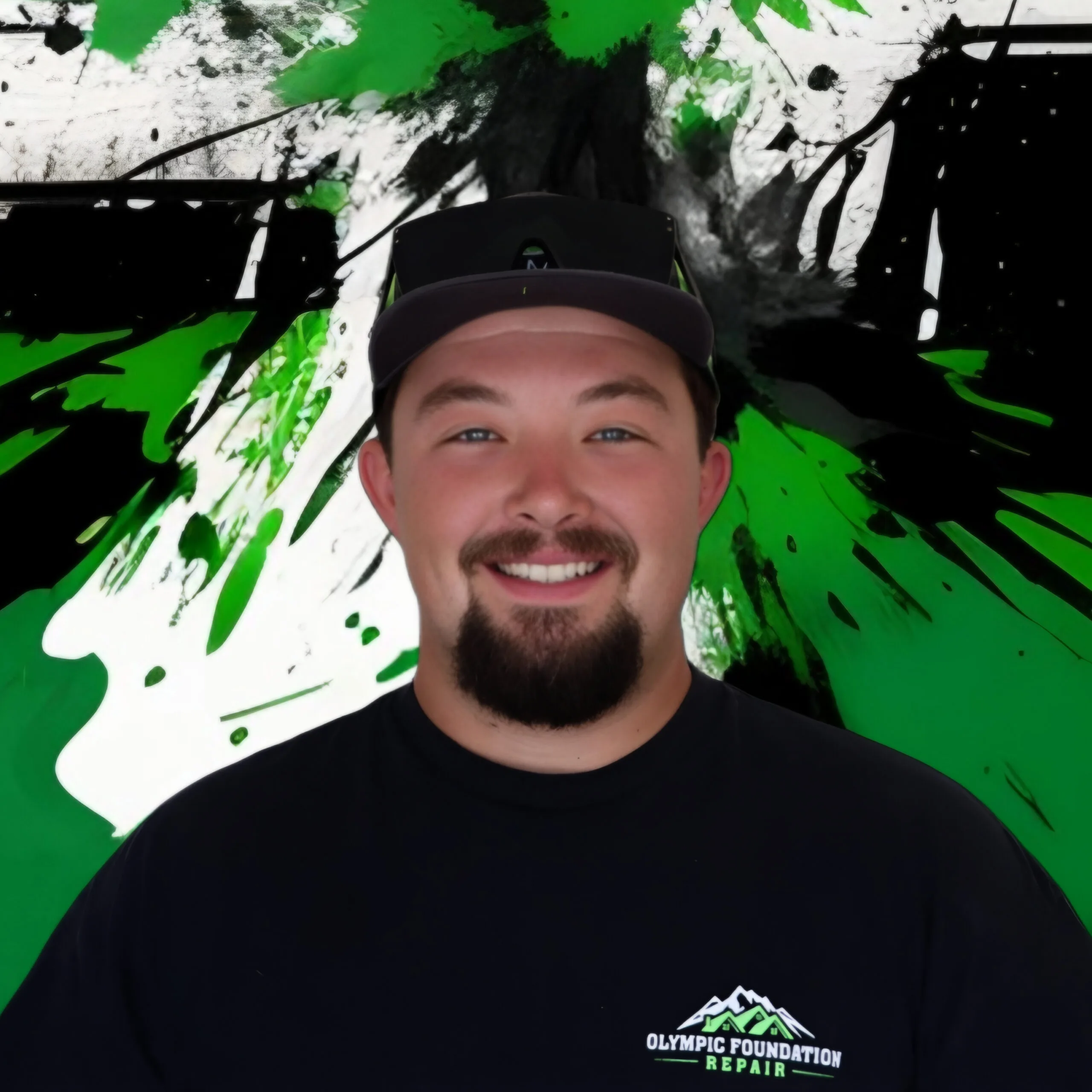 Selfie of a man wearing a dark cap and black shirt with an Olympic Foundation Repair logo, against a green/black/white abstract mural background